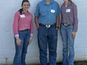 Three young people standing against a white cinderblock wall wearing Western shirts and jeans, with name tags