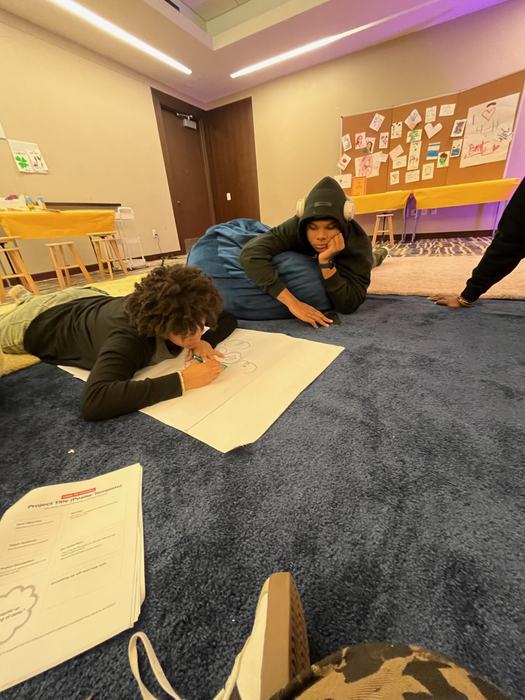 Two teenagers work together on a diagram.