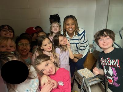 Group of children and an adult smiling near trays of eggs and a walker
