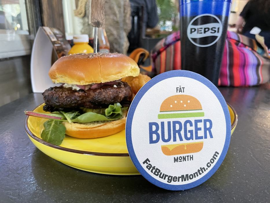 A burger with a Fat Burger Month coaster.