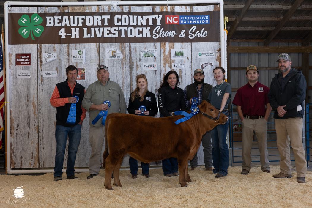 youth with their animal and buyers in front of banner
