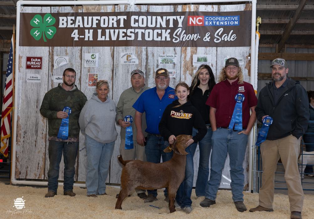 youth and their animal with buyers in front of banner