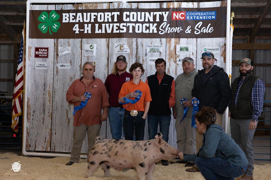 youth with animal and their buyers in front of banner