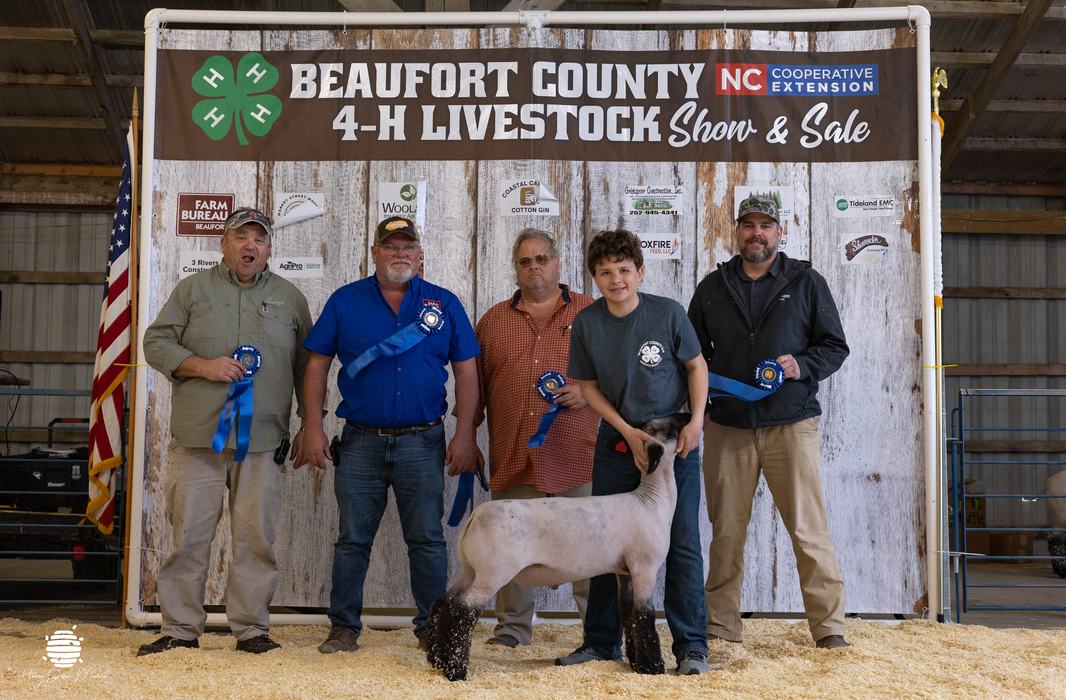 youth and their animal with buyers in front of banner