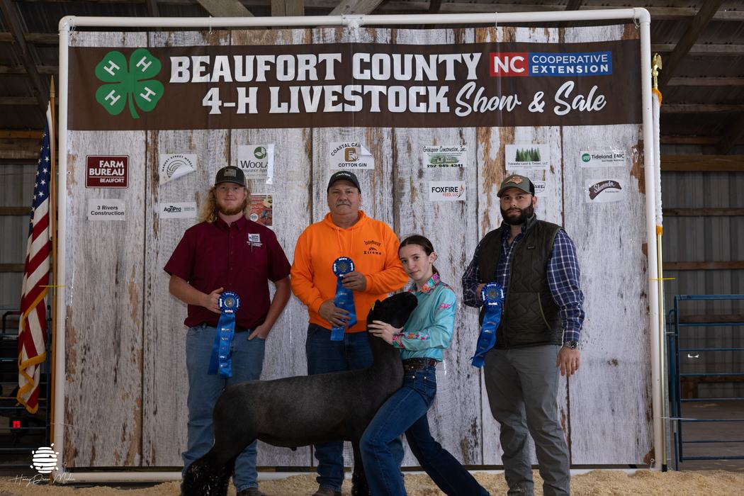 Youth and animal in front of banner with buyers