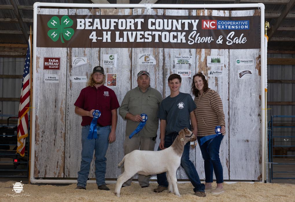 youth with animal and buyers in front of banner