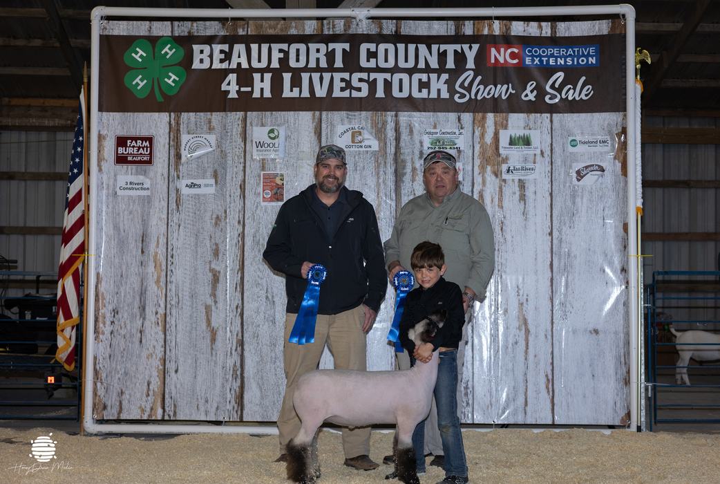 youth and animal with buyers in front of banner