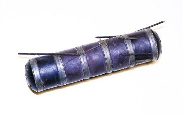 Small blue cylindrical electronic component wrapped in tape with two metal tabs and wires