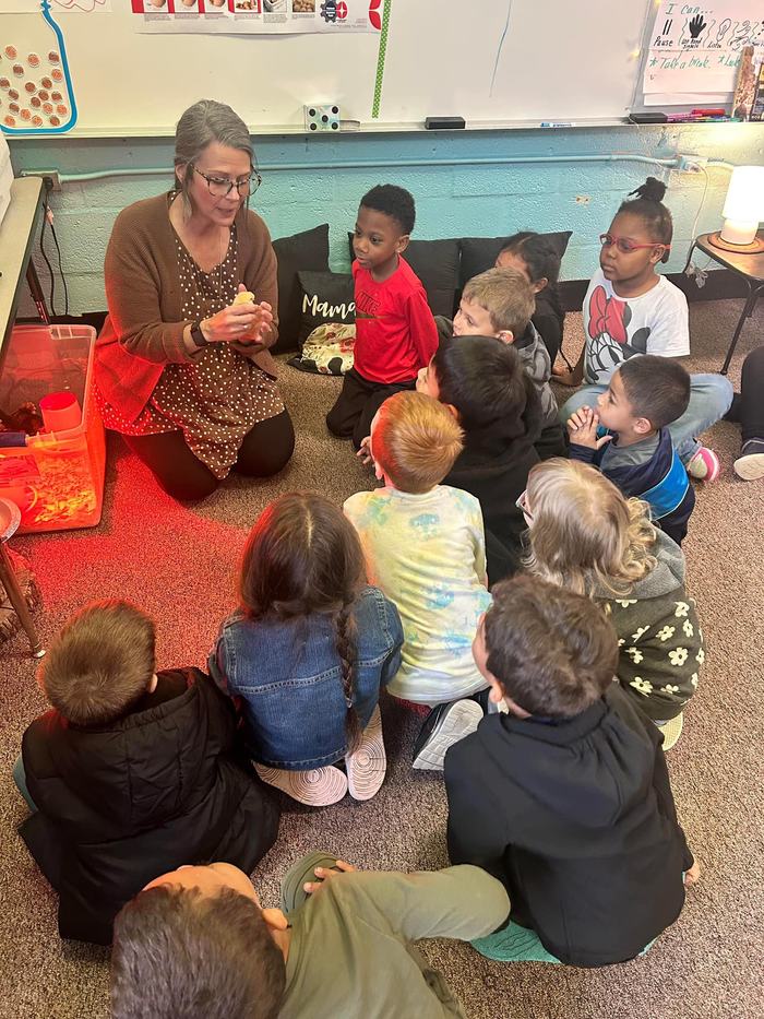 woman holding a chick while her students look on