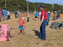 Child practicing lassoing a dummy steer while adults watch in a rodeo arena