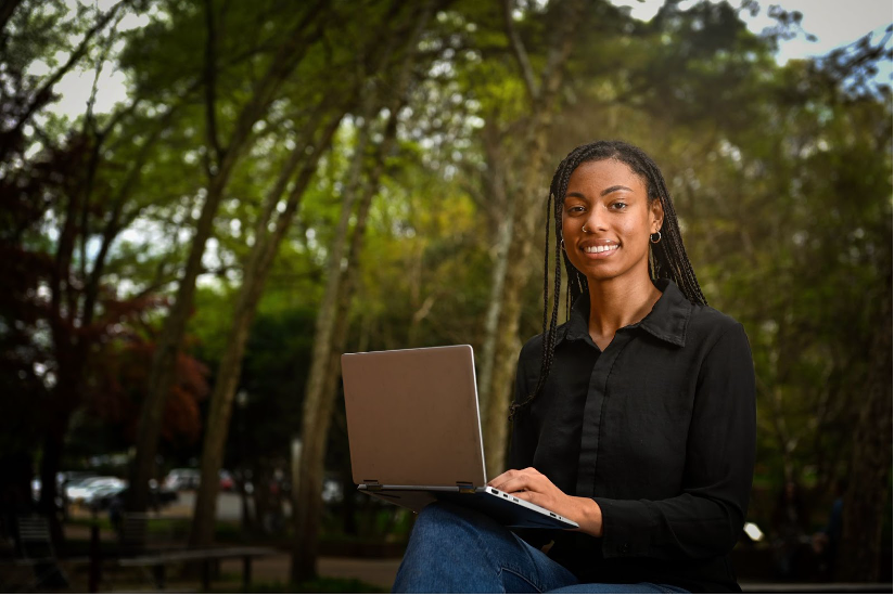 A woman with a laptop working in the field.