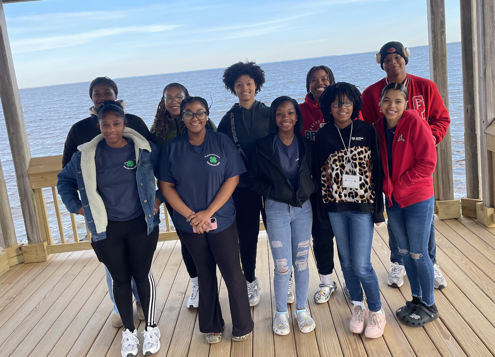 Students pose together by a large body of water.