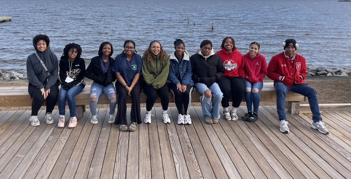 Students pose together on a shoreline.