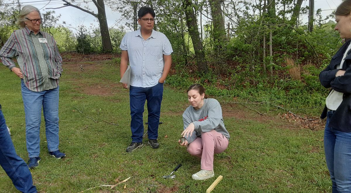NC State University graduate student Carlee Epting demonstrates tools and techniques on obtaining a soil sample for testing. 