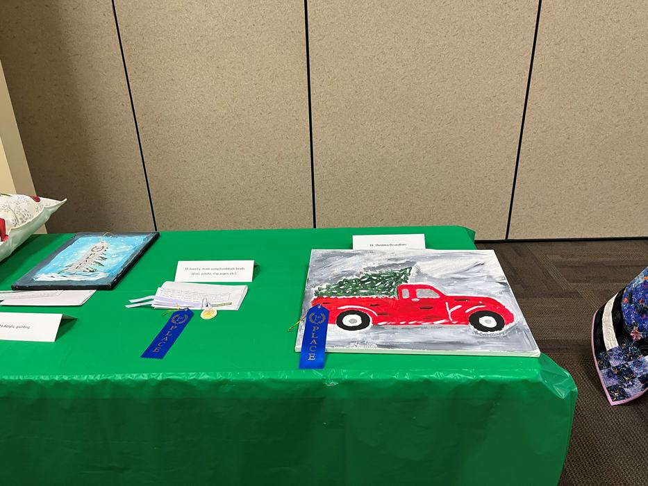 Red truck painting with Christmas tree on green table and blue 1st-place ribbon