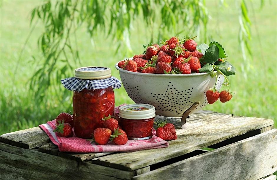 Fresh Strawberries and jam on a wooden table.