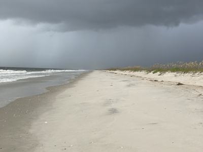 Sandy beach shoreline with waves and dark storm clouds approaching