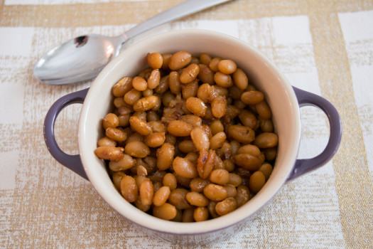 Dark brown beans in a purple ceramic pot.
