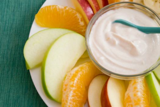 Apple and orange slices with a white yogurt dip.