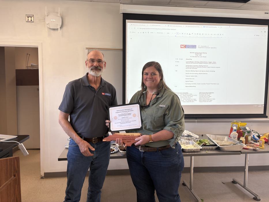 People posing with wooden North Carolina award and certificate