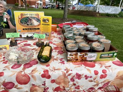 Jars of preserves in Ball Mason Jars on table beside sign reading "GOAT CHEESE"