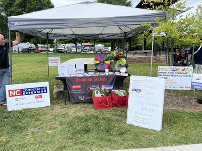 Outdoor donation station tent with NC Cooperative Extension signs and produce donations