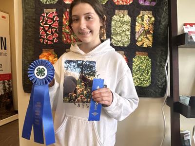 Photo of a girl holding two blue ribbons & horse photo