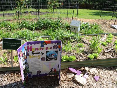 Raised garden bed with sign "North Henderson High School BOOST Garden" and board "Henderson County Strong"