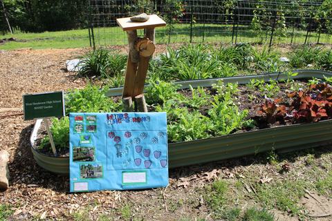 Raised metal garden bed with sign "West Henderson High School BOOST Garden" and student poster