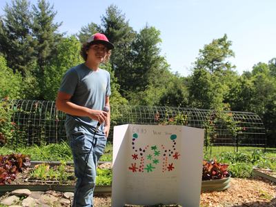 A student stands beside a poster presentation.