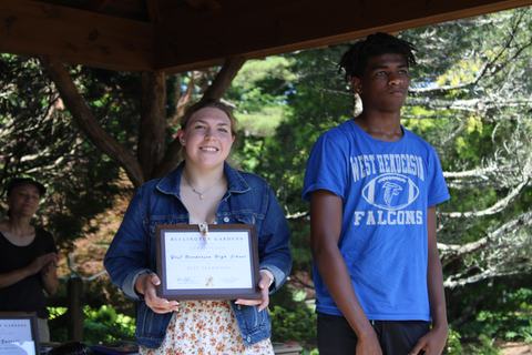 Two students hold an award they have recieved.
