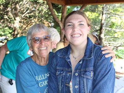 Two women pose together under a shelter.