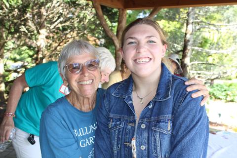 Two women pose together under a shelter.