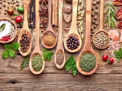 Wooden spoons arranged on a wooden table holding various spices and herbs