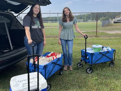 two peopling smiling and posing by wagons full of taste test materials