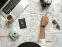 map with passport, camera, sunglasses, and laptop on top