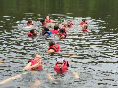 kids in lifejackets floating in lake