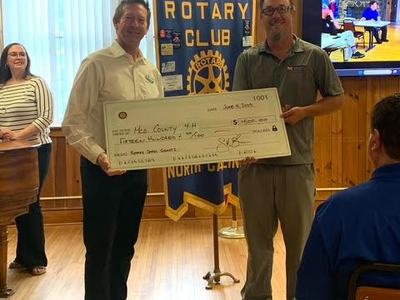 Two men hold a check, signifying a donation to the county center.