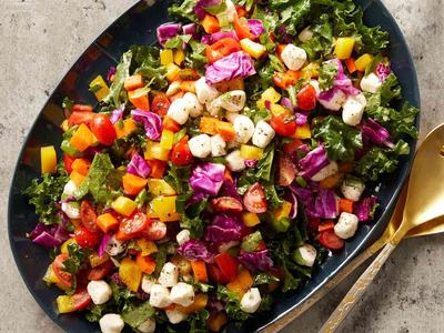 A salad of greens, tomatoes, cheeses, and other vegetables.