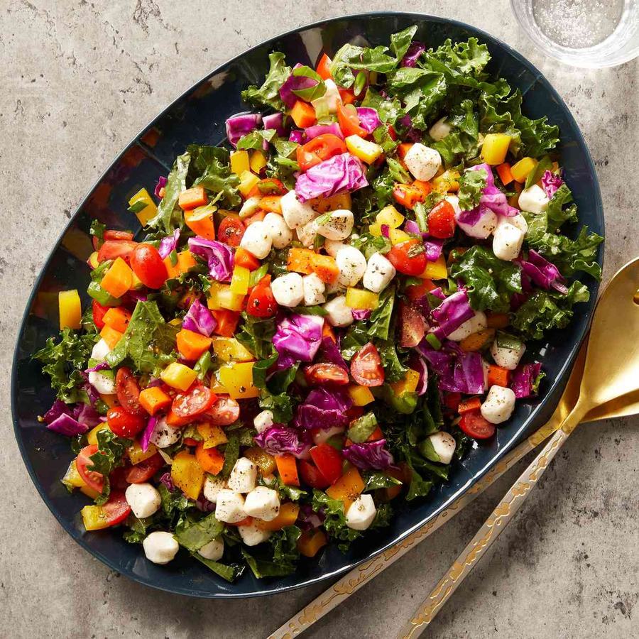 A salad of greens, tomatoes, cheeses, and other vegetables.