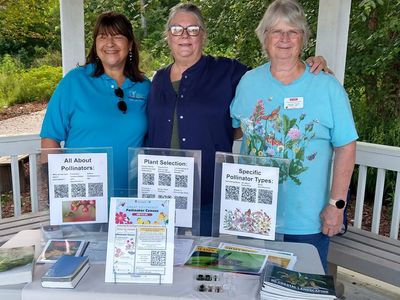 Three Master Gardener volunteers at info table labeled "Extension Master Gardeners."