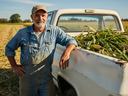 Farmer standing next to a truck with corn in the bed of the truck