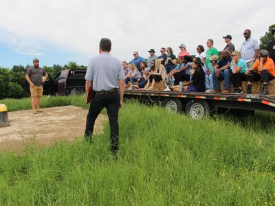 Farmer Josh Eudy and Soil and Water Conservationist Andy Cranfill address attendants around water unit where his cows get water while out in the pasture.