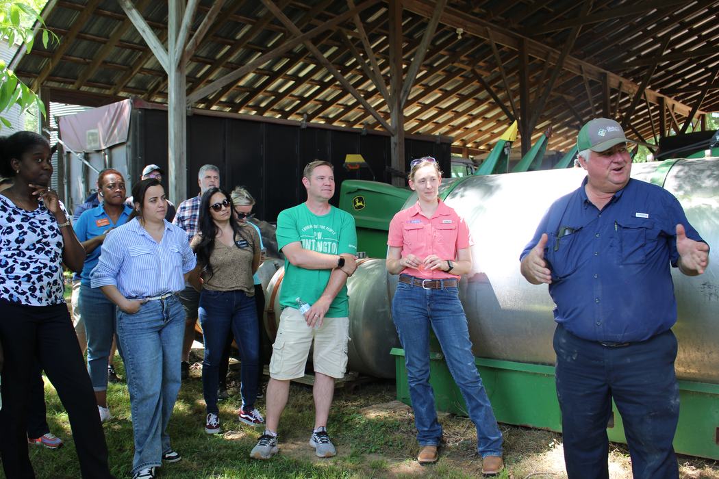 Farmer Randy Baucom speaking to attendance in front of large farm machinery used on row crops.