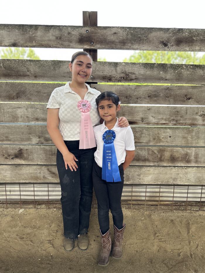 Sabella Rodgers and Victoria Vargas posing together with their sixth and first place ribbons after the dairy show