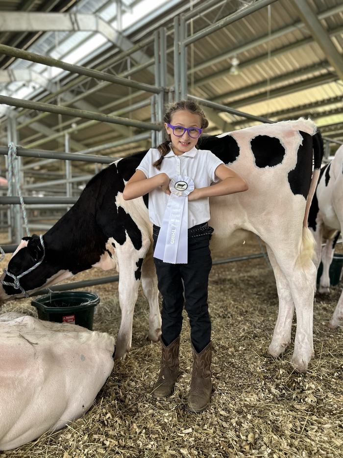 Yoshiko Clifton standing next to her dairy calf and holding her third place ribbon