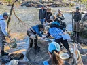 Group of people at riverbank collecting and examining aquatic samples
