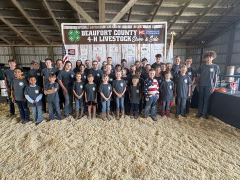 photo of youth standing in front of a banner that says Beaufort County 4-H Livestock Show & Sale