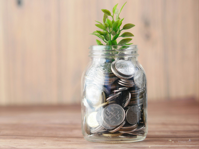 Budgeting Tips for the Season. Mason Jar with coins and plant growing out of top of glass.