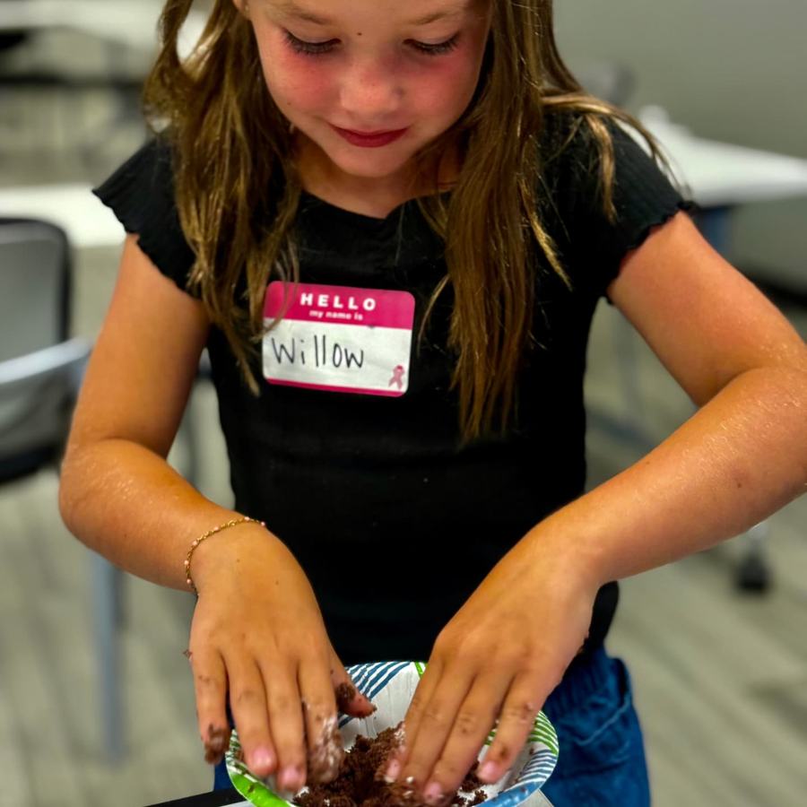 A girl mashes cake into a bowl by hand.
